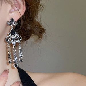 Detail of vintage silver drop earrings with black stones worn on a model's ear