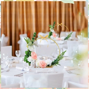 Floral gold metal hoop centerpiece with pink and white roses on a wooden base