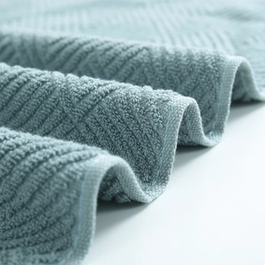Thick light blue cotton towel featuring geometric jacquard waves and soft plush texture