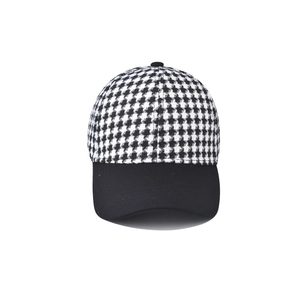 Detailed close-up of black and white houndstooth plaid fabric and black visor on baseball cap