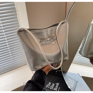 Detail of silver metallic tote bag featuring a decorative bow and long shoulder straps