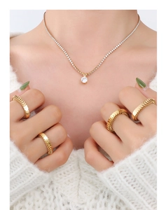 Detail of gold zircon tennis necklace and scale texture rings on model neck and hands