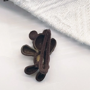 Détail de la pince à cheveux ours marron floquée avec clip en métal sur tricot doux