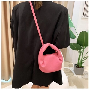 Rear view of a model wearing a pink padded ruched crossbody cloud bag with slim shoulder strap