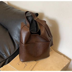Makroansicht einer braunen Vintage-Eimertasche auf Steinsockel mit minimalistischer Textur