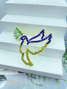 Golden peace dove brooch with blue and yellow rhinestones holding a green olive branch