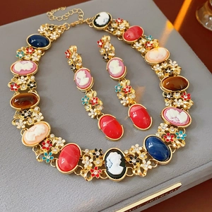 Close-up of vintage cameo jewelry set with colorful stones and floral details on velvet