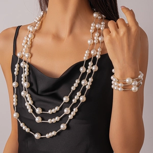 Vue détaillée du collier de perles à trois rangs et du bracelet sur une robe en soie noire