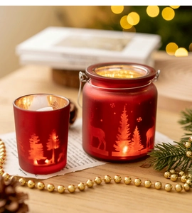 Détail du photophore de Noël en verre rouge dépoli avec silhouettes de rennes et de cèdres