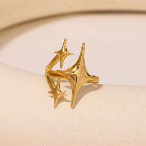 Polished gold stainless steel ring with minimalist starburst design on white pedestal