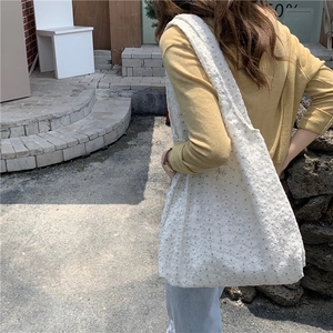 Detail of white floral embroidery on lace tote bag with a wide shoulder strap style