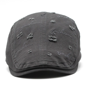 Detail of distressed dark gray cotton beret featuring fashion embroidery and torn effects