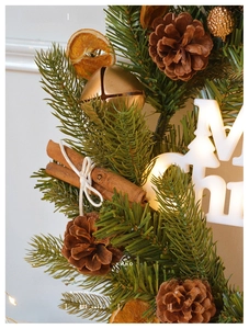 Detailed close-up of a Christmas wreath with pine cones, cinnamon, and LED lights
