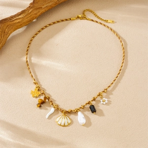 Detail of gold woven necklace featuring maple leaf, shell, pearl and flower charms