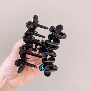 Dettaglio di una molletta per capelli a farfalla in plastica nera lucida con denti