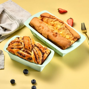Light green silicone loaf pans with fresh cakes and pastries on a yellow background