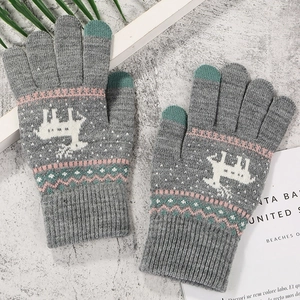 Close-up of gray knitted gloves with reindeer pattern and touchscreen-friendly fingertips