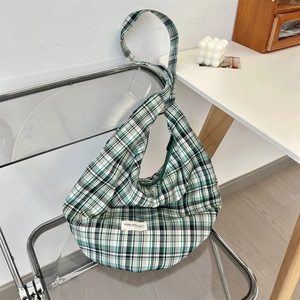 Detail of green and white plaid canvas hobo bag hanging on a modern chair