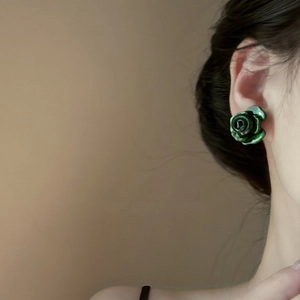 Close-up of deep green glazed rose flower stud earring worn on a model's ear