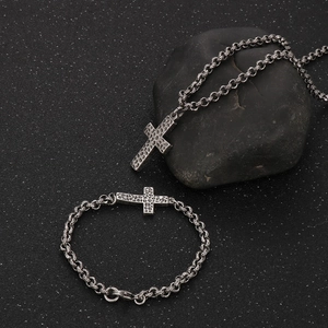 Close-up of vintage distressed stainless steel cross necklace and bracelet set