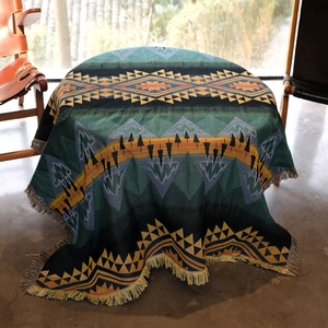 Bohemian style knitted picnic blanket with green mountains pattern and colorful tassels