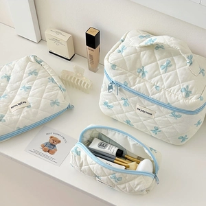 Three-piece quilted cotton cosmetic bag set with light blue bow patterns in cream white