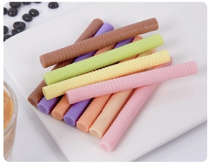 Macro view of colorful macaron chocolate wafer sticks displayed on a white plate
