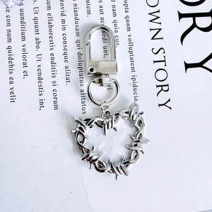 Punk style silver heart keychain with thorn texture and secure lobster clasp hanging on magazine