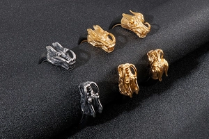 Macro detail of dragon head rings in gold and silver finish on black leather stand