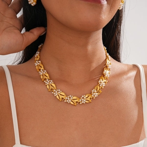 Macro detail of leaf-shaped necklace with white pearls and vintage gold plating finish