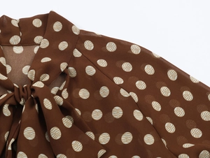 Détail d'une blouse en mousseline à pois avec col à nœud et épaules drapées fluides