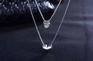 Detailed close-up of double-layer necklace with zircon round and heart pendants