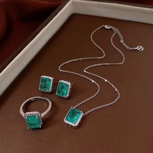 Macro view of silver jewelry set with square emerald stones and diamond halo detailing
