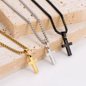 Polished stainless steel cross necklaces in gold, silver, and black on stone display