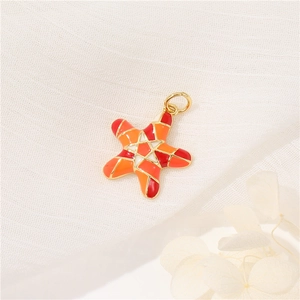Starfish pendant in 14K gold with vibrant orange red enamel on a soft white background