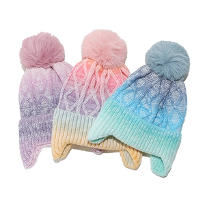 Drei Strickmützen mit Farbverlauf, Ohrenklappen und Bommeln für den Winter