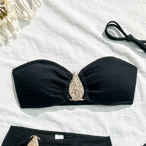 Detail of black bikini top with gold teardrop clasp and textured ruched fabric in size S