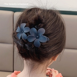 Detail of greyish-blue floral hair clips on hair bun showing matte texture and elegant style