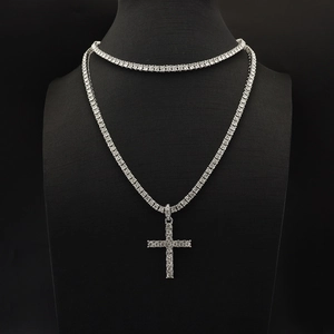 Silver tennis chain with a sparkling cross pendant shown on a professional black bust