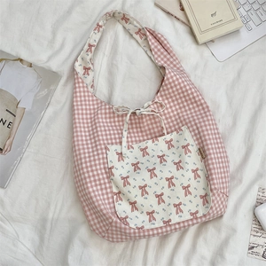 Gros plan d'un sac cabas en vichy rose avec poche à motif fleuri et nœud en tissu doux