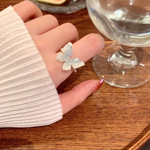 Detailed view of an elegant silver butterfly ring with shimmering wings on model's hand