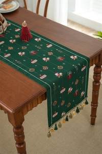 Detail of green Christmas table runner with snowman jacquard patterns and tassels
