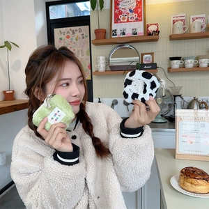 Detail of mini plush cosmetic bags in solid light green and cow print with soft fleece
