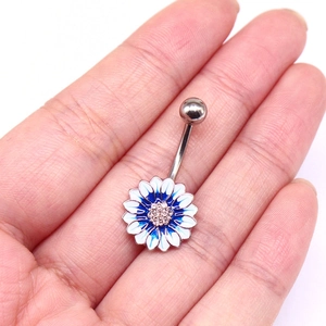 Nahaufnahme des Bauchnabelpiercings mit blau-weißem Gänseblümchen-Anhänger in der Hand