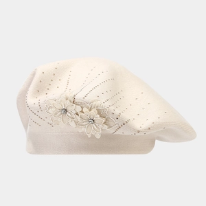 Detailed view of knitted beige beret featuring 3D floral accents and sparkling rhinestones