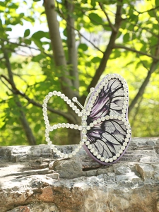 Detail shot of the butterfly-shaped handbag with purple patterns and sparkling rhinestones