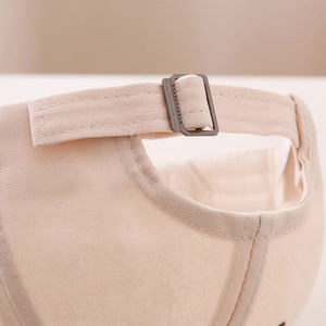 Macro view of adjustable metal buckle and stitching detail on beige cotton kids baseball cap