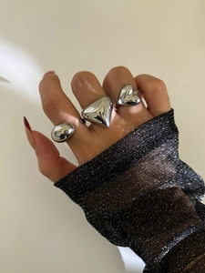 Macro detail of three polished silver chunky rings featuring heart and geometric shapes