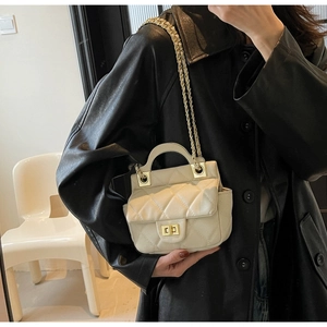 Close-up of cream quilted handbag featuring gold twist-lock and elegant chain strap detail