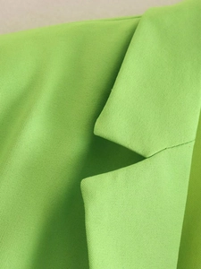 Close-up detail of the collar and shoulder seams on a grass green blazer jacket